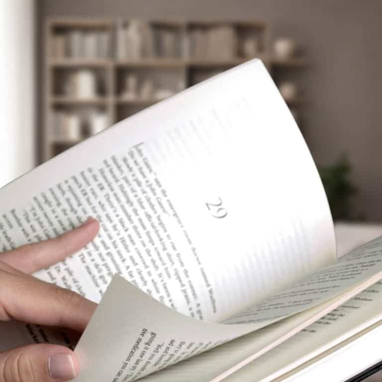 Close-up of hands paging through a book in front of a bookshelf