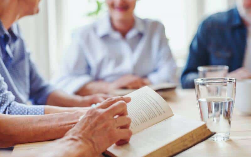 People sitting around a table discussing a book