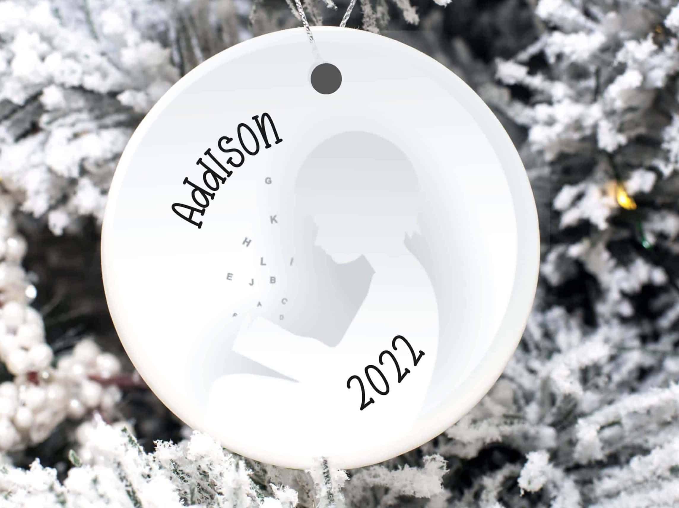 Ornament with the silhouette of a child reading, with the name Addison and 2022 printed on it