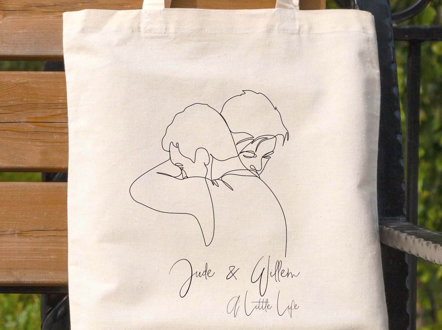 Tote bag with a line drawing of two men hugging, with text reading Jude and Willem, A Little Life