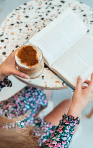 Close up of a someone reading a book while holding a coffee